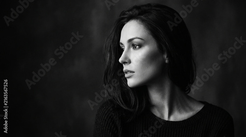 Thoughtful young woman looking away in dark black and white portrait perfect for illustrating emotional mental health and dramatic artistic beauty