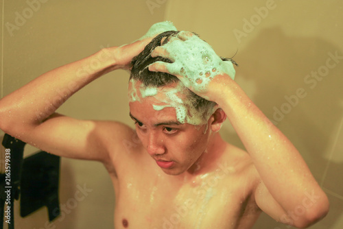 Quadro su tela Young Asian Man Washing Hair with Rich Shampoo Lather in Bathroom Shower