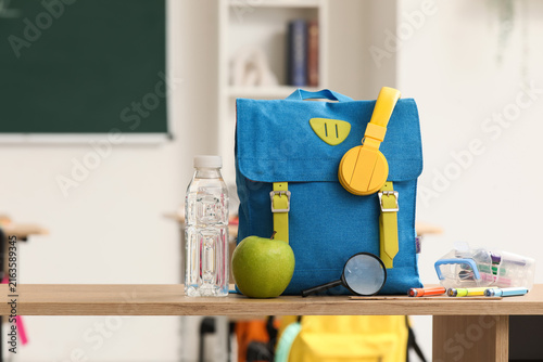Back to school with backpack healthy lunch and supplies on a classroom desk e...