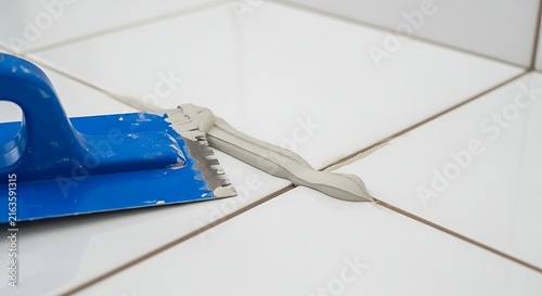 Blue Trowel Spreading Filler on White Tile Surface