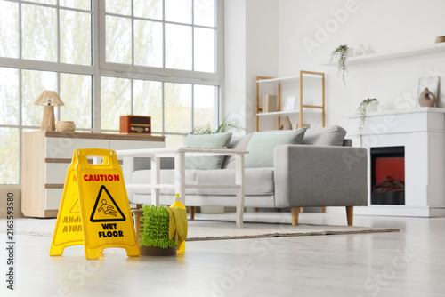 Bucket with cleaning supplies and caution sign in living room