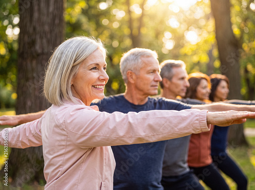 Bild auf Leinwand Happy group of diverse senior people practicing outdoor yoga or tai chi in a sunny park setting