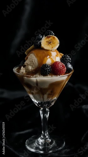 Salted caramel ice cream in a crystal dessert glass topped with caramelized banana slices and berries