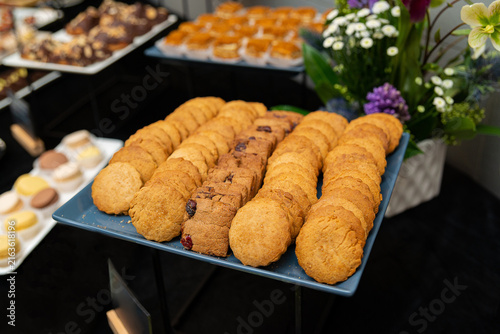 Quadro su tela Deliciously arranged cookies on a blue tray, with pastries and flowers nearby