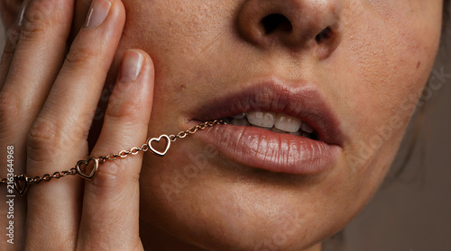 Close-up portrait of a beautiful woman featuring heart charm jewelry on her hand, symbolizing love and romance