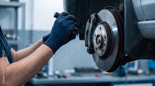 Professional mechanic inspecting car brake rotor with flashlight in automotive service workshop environment