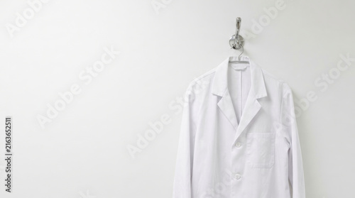 White lab coat hanging on wall represents labor shortage impact in healthcare and scientific work