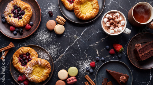 An inviting assortment of delectable pastries, colorful macarons, and a warm cup of hot chocolate, creating a delightful scene that appeals to all dessert lovers.