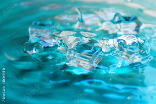Clear Ice Cubes In Turquoise Water With Splash And Ripple Texture