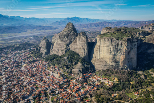 Kalambaka town nestled beneath the towering rock formations of Meteora, Greece, under clear blue sky.
