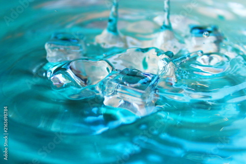 Clear Ice Cubes In Turquoise Water With Splash And Ripple Texture