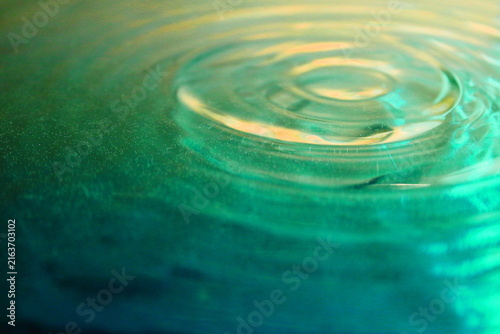 Concentric Water Ripples on Green and Gold Liquid Surface Close Up