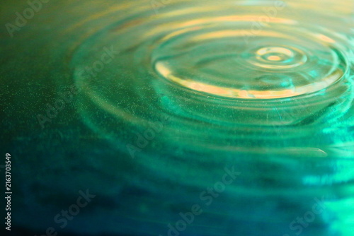 Concentric Water Ripples on Green and Gold Liquid Surface Close Up