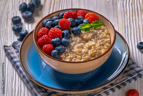 Schälchen mit eingeweichten Haferflocken und belegt mit Himbeeren und Blaubeeren