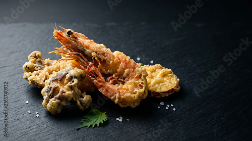 Crispy Golden Brown Tempura Platter Featuring Large Shrimp Squid and Sweet Potato Slices on a Dark Slate Surface with Sea Salt Garnish