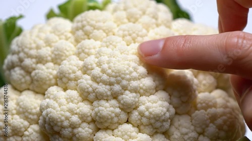 Close-up macro shot of a textured cauliflower floret with a finger pointing to its intricate pattern