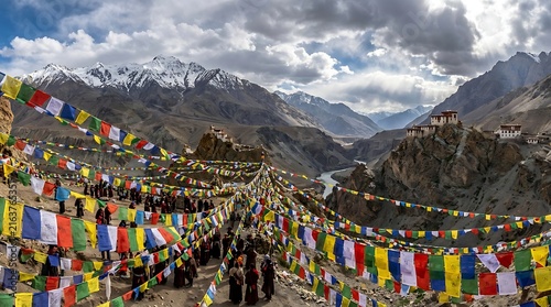 Colorful Buddhist prayer flags fluttering in the Himalayan mountains of Ladakh India with snow-capped peaks and a valley in the background.