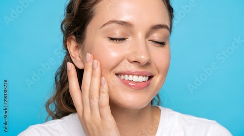 Close up smiling woman touching cheek with healthy skin blue background