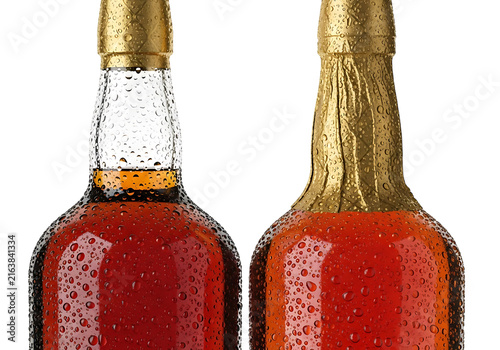 Two glass bottles of amber liquid, one with gold foil cap, covered in water droplets, studio shot