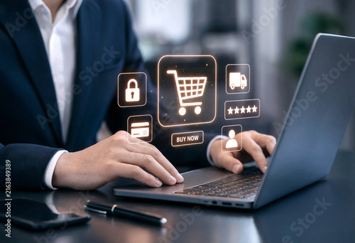 Business professional using a laptop with online shopping icons floating above the screen