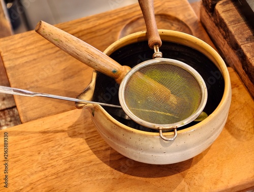 Cuadro en lienzo A close-up view of traditional matcha green tea tools, featuring a fine mesh sifter and metal scoop on a handcrafted ceramic bowl