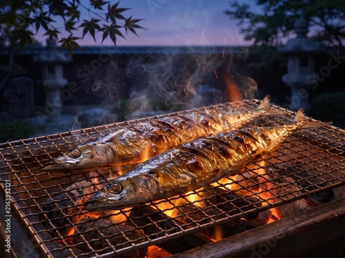 Obraz na płótnie 赤々とした炭火と立ち上る煙の中で香ばしく焼き上がる二尾の秋刀魚（サンマ）と秋の庭