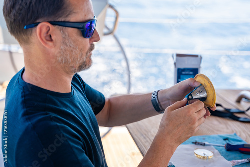 Canvastavla Man repairing yacht equipment with hand tools during a sailing trip on the Adriatic Sea