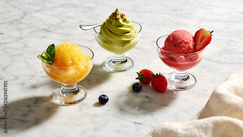 Fresh summer fruit platter with berries and citrus in elegant glass bowls on marble table