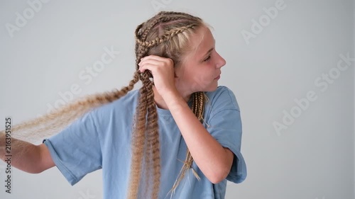 The girl is unbraiding her braids. Her hair has become curly.
