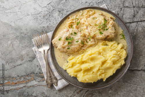 German Zwiebel schnitzel pork cutlets with a rich onion cream sauce with mashed potatoes closeup on the plate on the table. Horizontal top view from above