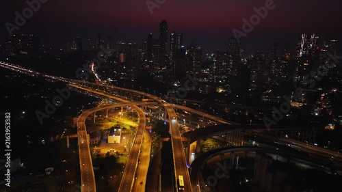 Drone hyperlapse aerial shot of Atal Setu in Mumbai at night, showcasing the dynamic cityscape illuminated with vibrant lights. The footage captures the fast-paced movement of traffic and clouds.