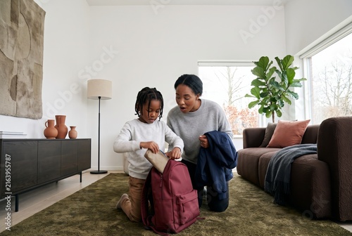 Child packing a school backpack in the living room before the first day of school