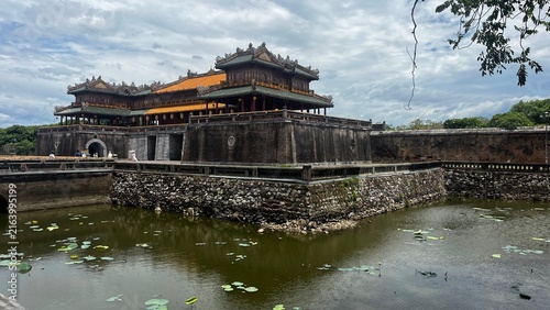 Cuadro en lienzo Scenic view of the ancient Ngo Mon (Meridian Gate), the main entrance to the Imperial City and Citadel in Hue, Vietnam, featuring a stone moat with water lilies under a cloudy sky