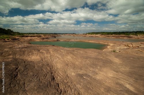 A rocky outcrop in the middle of the river, revealing the water and a cloudy sky.