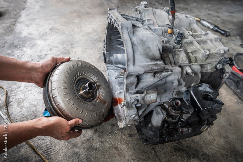 Auto mechanic removing a torque converter from an automatic transmission.