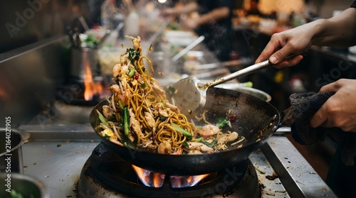 Professional Chef Stir-Frying Fried Noodles in a Hot Wok. Asian Cuisine Cooking Technique, and Restaurant Kitchen Concept