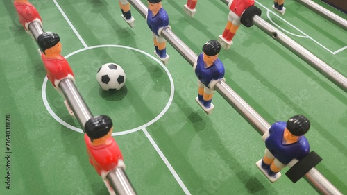 Cuadro en lienzo Detailed close up of foosball players surrounding a miniature soccer ball on a traditional football table, representing competition, teamwork, strategy, sports recreation, gaming, entertainment