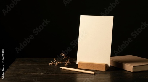 Blank White Card on Wooden Stand Against Dark Background With Copy Space