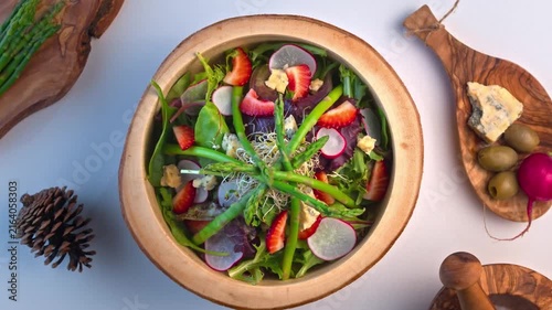 Gourmet fresh green salad with strawberries and asparagus top view bowl video