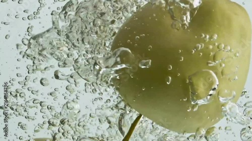 Green apples plunging deep underwater with bubbles