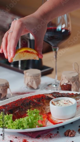 hand sprinkle baked mackerel fish with red paprika and lemon juice in restaurant