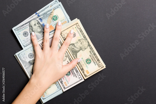 Cuadro en lienzo Female hand lying on stack of various dollar bills on colorful background