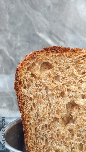 Vertical Shot Golden Crust Whole Wheat Artisan Sliced Bread Texture. A close-up view showing the airy crumb, rustic caramelized crust, and natural grain texture of baked sourdough wheat bread.