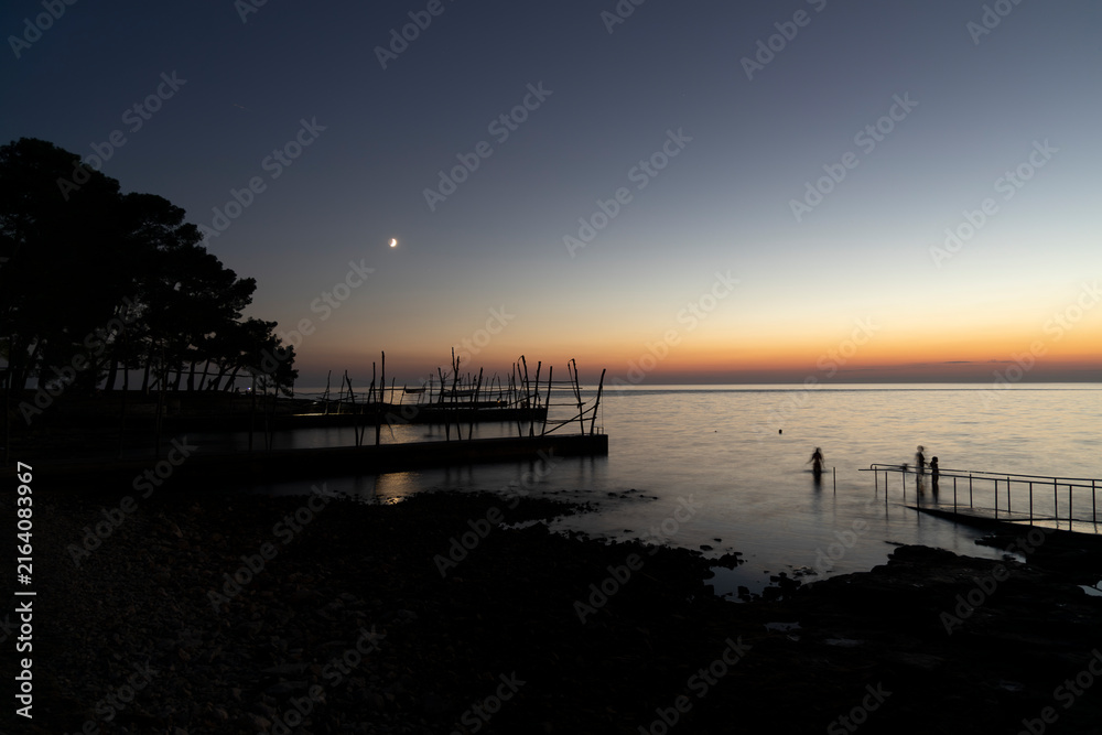 Obraz premium Crescent Moon Over Adriatic Sea at Dusk with Traditional Fishing