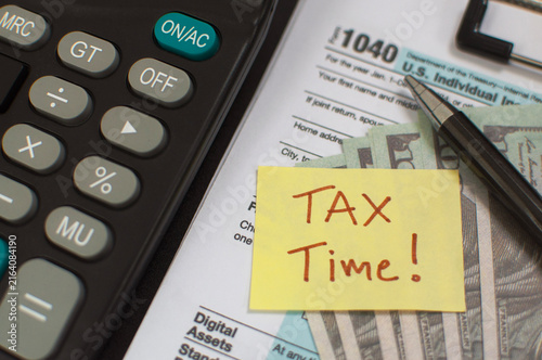 Tax season preparation with calculator and sticky note reminder on paperwork, Business concept financial planning for future tax season in 2027 digital calculator displaying tax deadline.