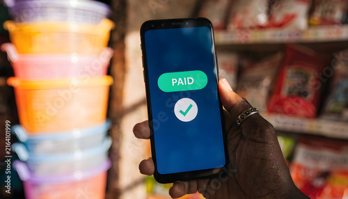 Mobile Payment Success Screen Displaying Paid Badge on Smartphone inside Local Supermarket