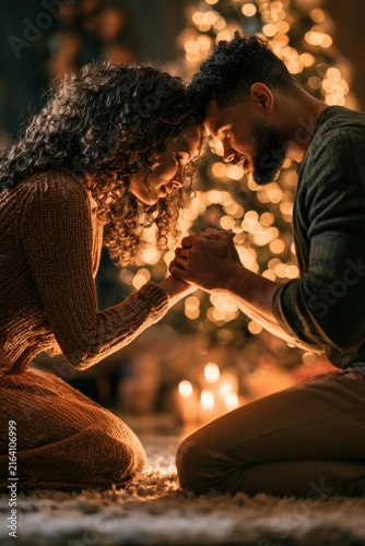 Couple Praying Together Beside Glowing Christmas Tree