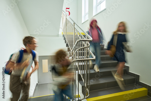 Foto Caucasian kids running down school stairs with motion blur, representing active student life