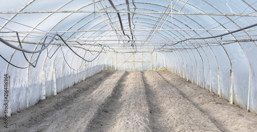 The interior of a greenhouse with soil prepared for planting.