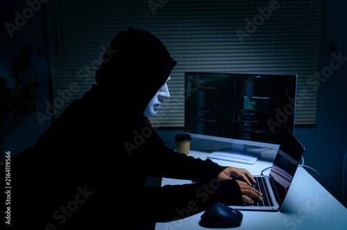 Fotografía Hacker identity theft concept wearing anonymity mask while using laptop for cybe